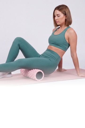 Woman in green BERNESSI activewear resting with a foam roller